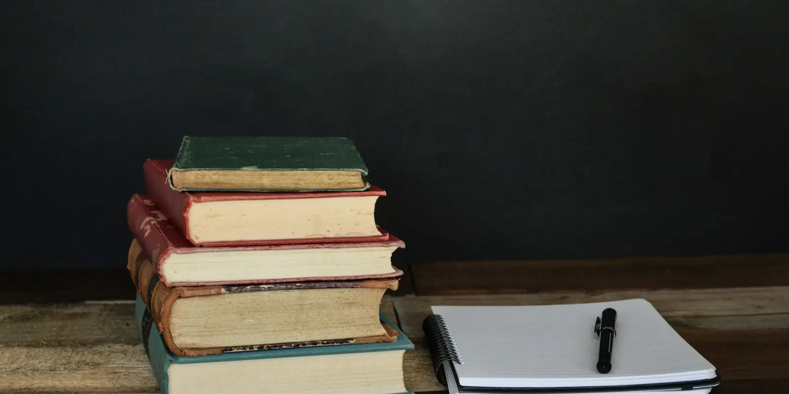 temario auxiliar administrativo estado Libros apilados junto a un cuaderno y un bolígrafo